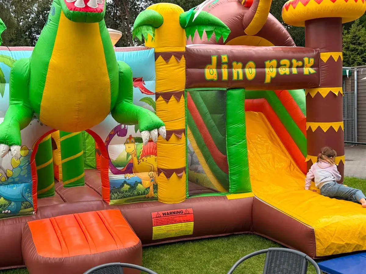 Een kind op de glijbaan van het springkussen bij het gildepaviljoen